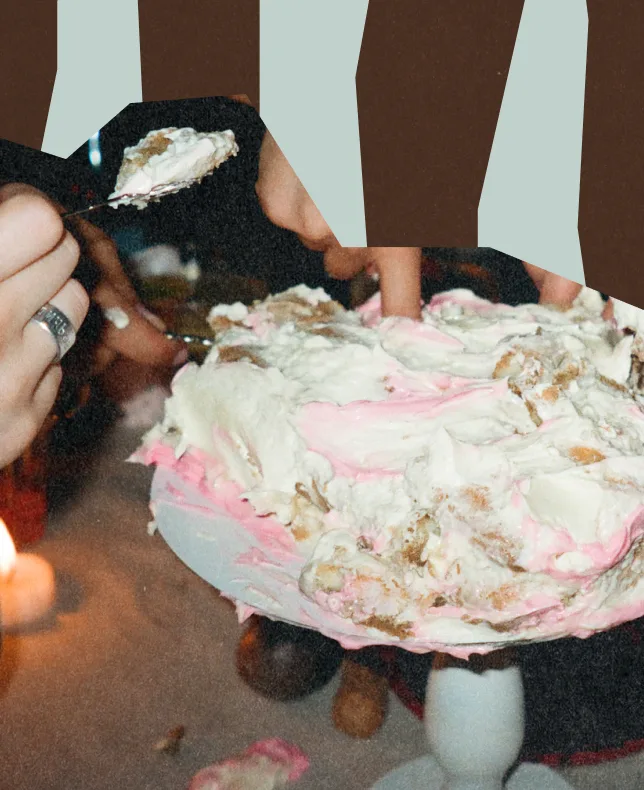 Hands pulling apart a frosted pink and white cake.