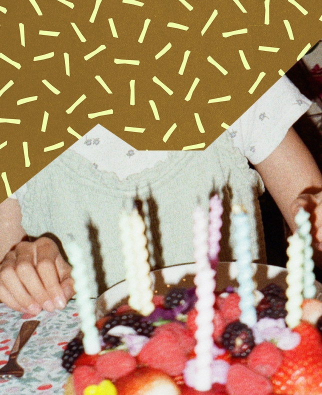 A child's hands reaching for a fruit-topped birthday cake with candles, against a confetti background.